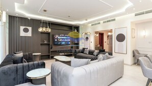 A modern living room with a large flat-screen TV, a sofa, a coffee table, and a TV stand. - Holidays R Us villa 3 bedroom premium location (Dubai)