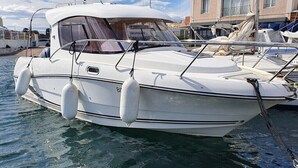 A white motorboat docked at a marina with a covered cabin and a cabin window. - UNUSUAL NIGHT ABOARD A BOAT (Saint-Florent)