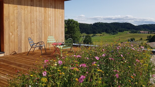 Eine Holzterrasse mit Sitzgelegenheiten und Blick auf eine ländliche Landschaft.