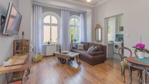 Una sala de estar con un sofá marrón, una mesa de centro de madera, un televisor y un comedor con una mesa y sillas.