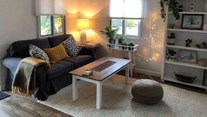 A living room with a dark sofa, a wooden coffee table, and a white bookshelf. - The Cwtch - Cosy Home, with Breakfast Basket (Little Hartley)