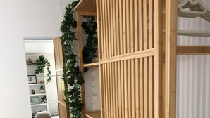 A room with a wooden wardrobe, a mirror, and a hanging plant. - The Cwtch - Cosy Home, with Breakfast Basket (Little Hartley)