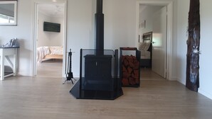A modern living room with a black fireplace, a bed, a TV, and a wooden floor.