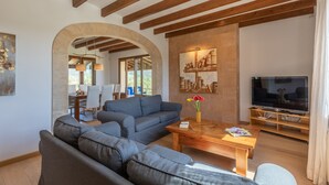 A modern living room with a sofa, a coffee table, and a TV. - Modern finca, secluded location, 10min to the dream beach Playa del Muro, large pool (Búger)