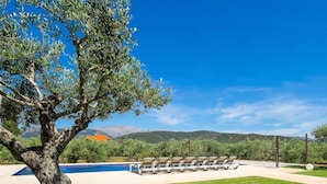 A poolside area with lounge chairs, a tree, and a mountain view in the background. - Modern finca, secluded location, 10min to the dream beach Playa del Muro, large pool (Búger)