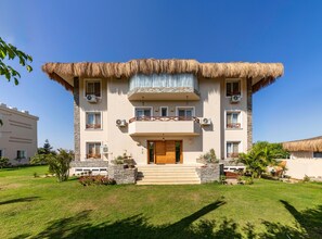 A two-story building with a thatched roof, stone facade, and multiple air conditioning units.