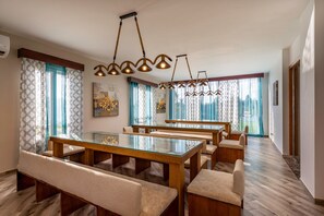 A spacious dining area with a long wooden table and multiple cushioned benches.