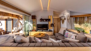 Een moderne woonkamer met een grote bank, een televisie en een houten salontafel.