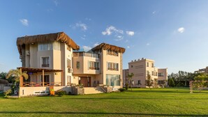 Een modern herenhuis met twee verdiepingen, een rieten dak, een balkon en een verzorgd gazon.