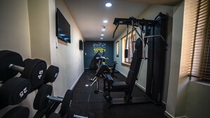 A gym with dumbbells, a bench, and a weight machine. - Khan Khediwe Hotel (Amman)
