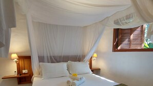 A bed with a canopy, two bedside lamps, and a wooden nightstand. - Beautiful house with 4 suites and swimming pool in Trancoso (sleeps 10 people) (TRANCOSO)