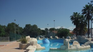 Une piscine entourée de formations rocheuses et de palmiers en arrière-plan.