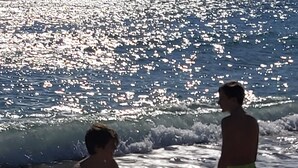 Deux personnes se trouvent sur une plage, et les vagues se rapprochent.
