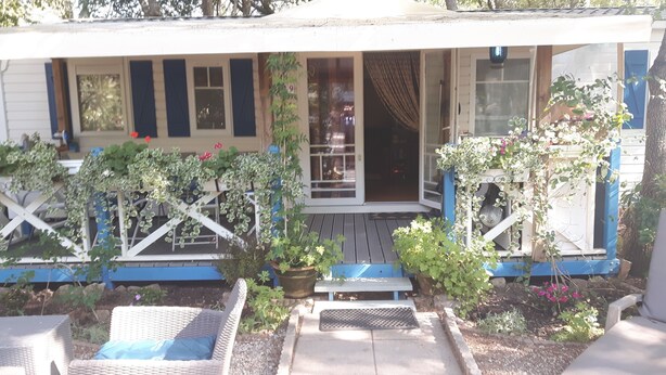 Une maison avec un porche, des plantes en pot et du mobilier d’extérieur.