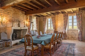 A rustic dining room with a wooden table, chairs, and a fireplace.