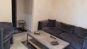 A living room with a grey sofa, a small round table, and a coffee table. - Cosy studio. (Mansourieh)