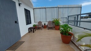 Un balcon agrémenté de plantes en pot, deux chaises en bois et une petite table.