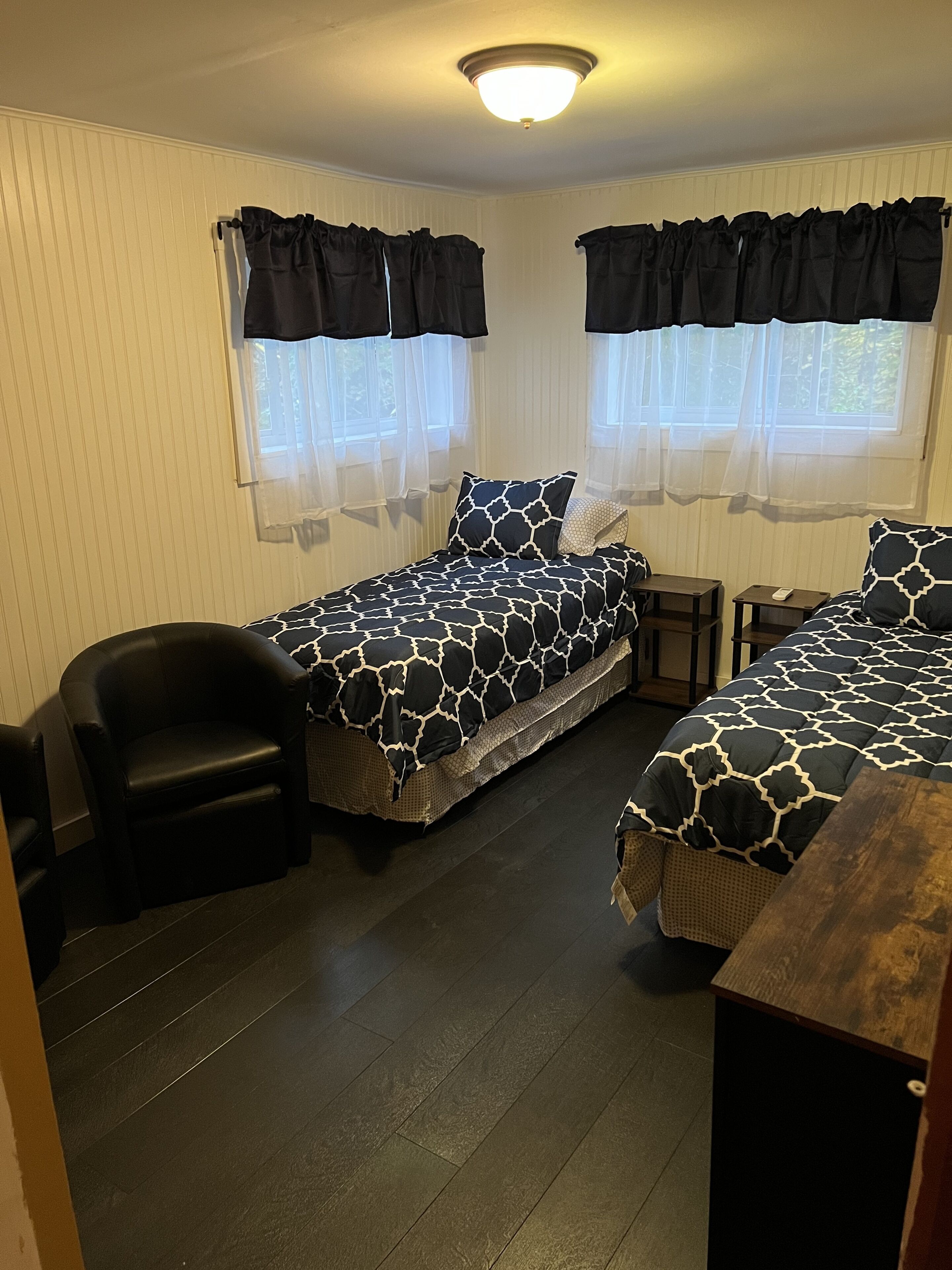 Une chambre avec deux lits, une chaise et une petite table.