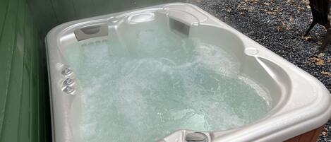 A hot tub with a wooden exterior, a control panel, and a small step leading into it.