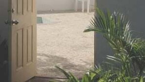An open door leading to a balcony with a view of the sea and a mountain.