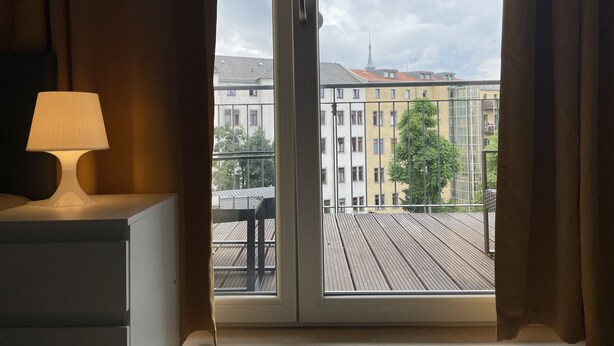 Ein Zimmer mit Blick auf einen Balkon und Gebäude.