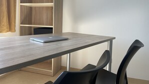 Ein modernes Zimmer mit einem Holztisch, einem Laptop und schwarzen Stühlen.