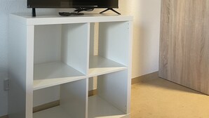 Ein weißes TV-Möbel mit einem Flachbildfernseher darauf, vor einer weißen Wand platziert.