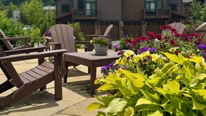 A lodge with a stone patio, wooden deck chairs, and a flower arrangement. - Updated Townhome | Private Hot Tub | Pool access (Keystone)