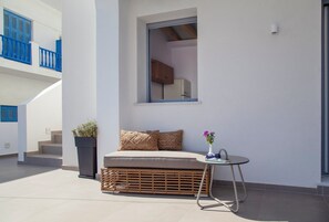 Un balcon avec un canapé, une petite table et une plante en pot.