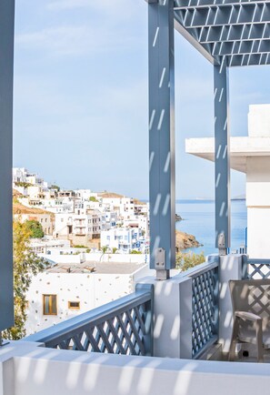 Un balcon offrant une vue sur une ville côtière, avec des bâtiments blancs et un ciel dégagé.