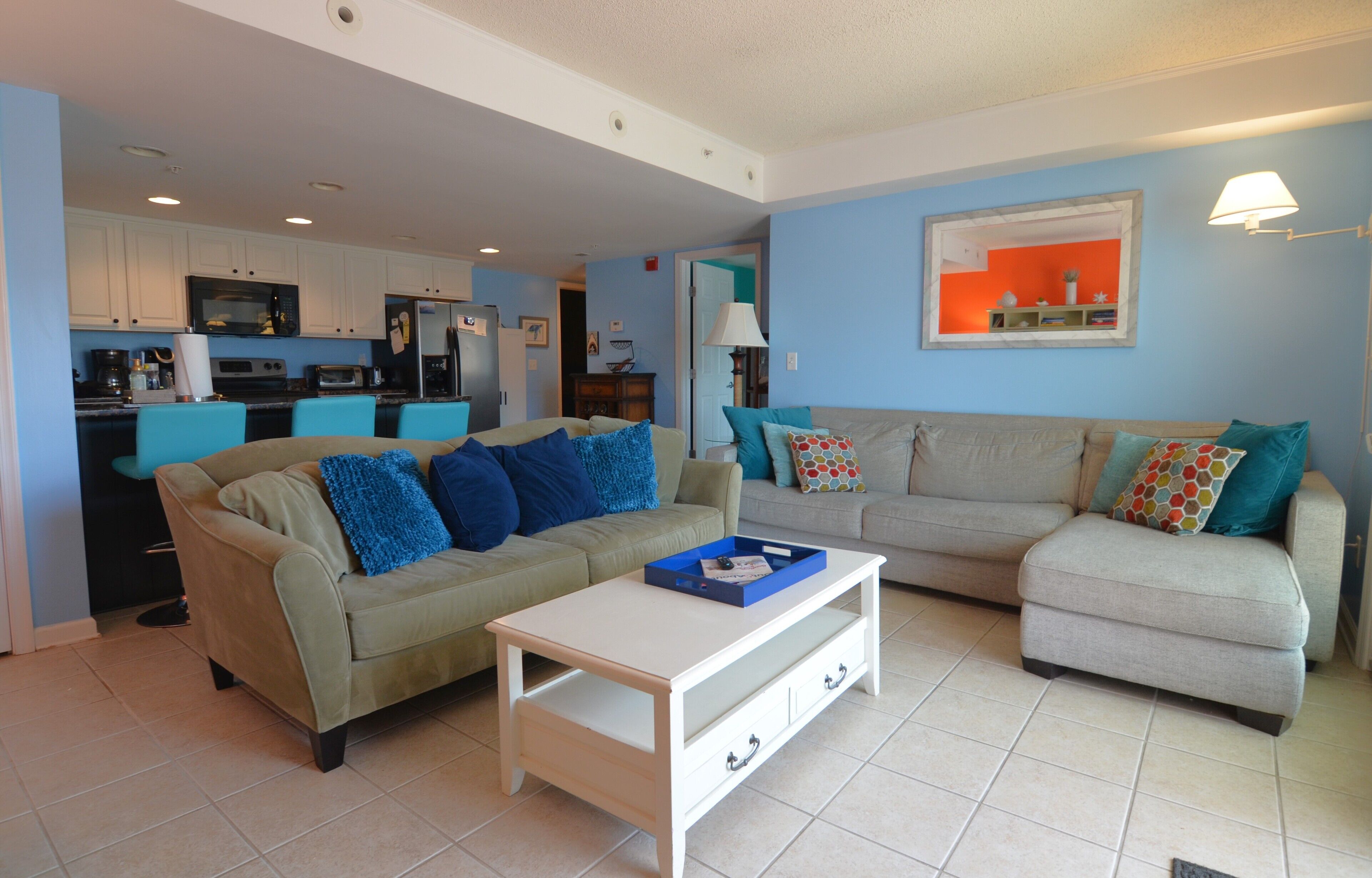 A living room with two sofas, a coffee table, and a kitchen in the background.