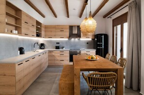Une cuisine moderne avec des meubles en bois, un îlot central et un coin repas doté de chaises en osier.