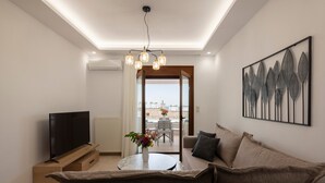 A modern living room with a sofa, TV, and a table with flowers. - Zen play apartment,pool,Near beach & amenities (Nea Magnisia)