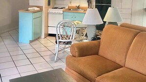 A compact living space with a sofa, a dining table, a kitchen area with a stove, and a TV.