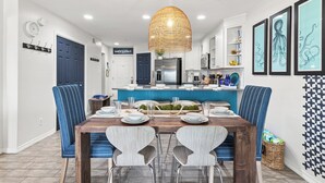 A modern kitchen with a central island, blue chairs, and a dining table set for four. - MARAVILLA "LUCKY TOO" BEAUTIFUL PRIVATE BEACH VIEWS END UNIT "BEACH SETUP DAILY" (Miramar Beach)
