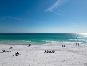 Ein Strand mit Personen, die sonnenbaden und auf Stühlen sitzen.