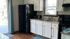 A kitchen with white cabinets, a black refrigerator, a stove, and a ceiling fan. - On a Whim, a family retreat! (Chincoteague)
