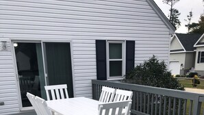 A white deck with a table and chairs, a sliding glass door, and a railing. - On a Whim, a family retreat! (Chincoteague)