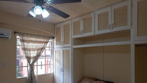 Una camera da letto con un letto, una ventola a soffitto e una finestra con tende.