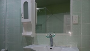 Un bagno con un lavandino bianco, un rubinetto con elementi in vetro e uno specchio sopra.