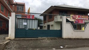 Edifici tancat per una reixa amb un cartell que anuncia 'Su Pollo Asado'.