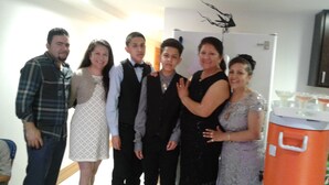 Un grup de persones en una habitació amb una paret blanca i un frigorífic.