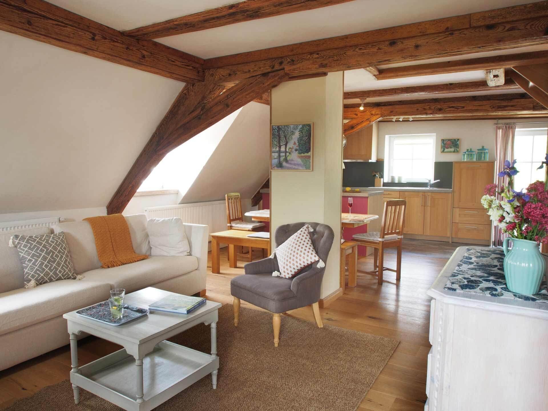Een gezellig loft appartement met zichtbare houten balken, een eethoek en een keuken.