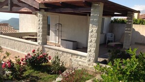 Un espace extérieur abrité, doté de piliers en pierre, d’une pergola en bois et offrant une vue sur les montagnes.