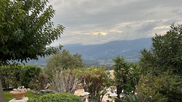 Un sentier qui mène à un belvédère offrant une vue panoramique sur les montagnes lointaines et un ciel nuageux.