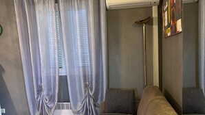 Un salon avec un canapé, une lampe sur pied et une fenêtre avec des rideaux.
