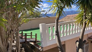 Un balcon doté d’une balustrade blanche, d’un mur végétal et offrant une vue sur les montagnes.