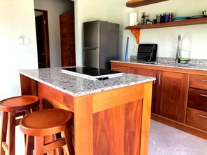 A kitchen with a granite countertop, wooden cabinets, a stainless steel refrigerator, and a built-in stove.
