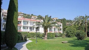 Hotel amb un jardí ben cuidat, un camí i una palmera.