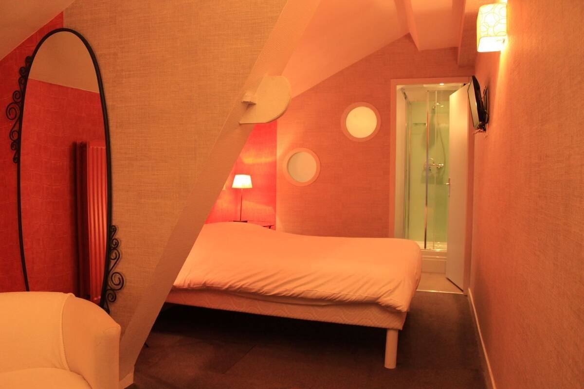 A bedroom with a bed, a mirror, and a door leading to a bathroom.